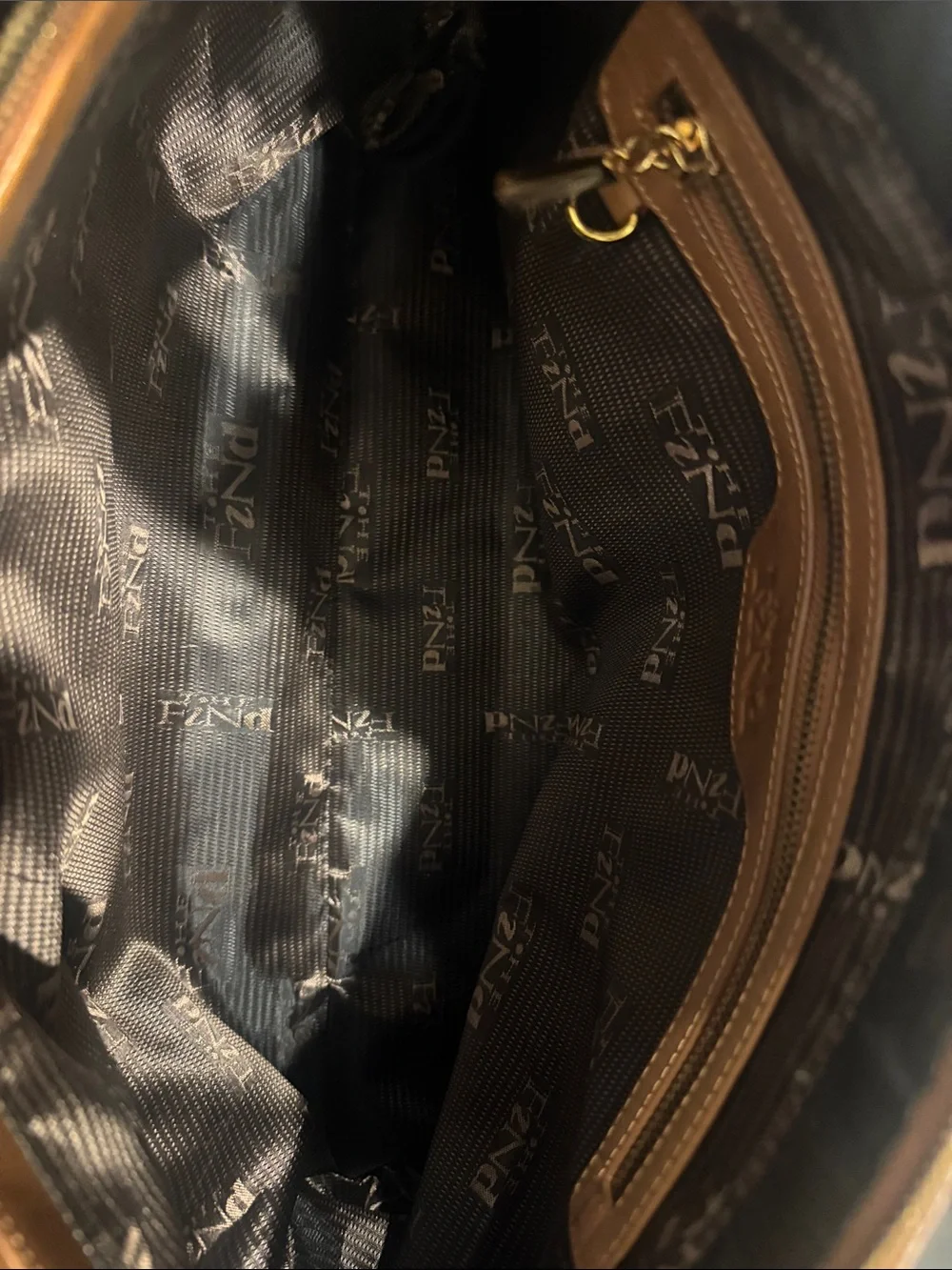 The Find Classic Tan Leather Weekender Travel Bag with Gold Hardware Buckle.